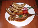 A picture of Fried sardine in coconut, tomato sauce and fried green bananas.