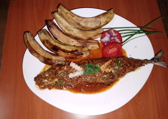 A picture of Fried sardine in coconut, tomato sauce and fried green bananas.