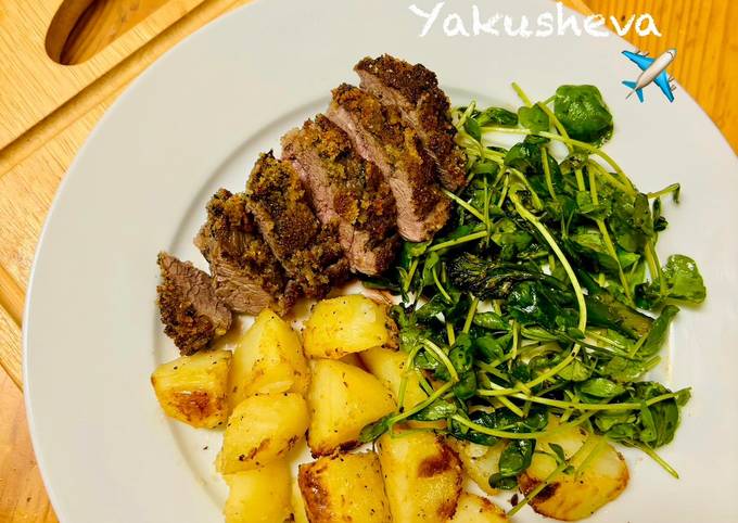 A picture of Pesto, Crusted Lamb Steak and Roast Potatoes with broccoli salad.