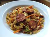 A picture of Sautéed cabbage and carrot with sausage.