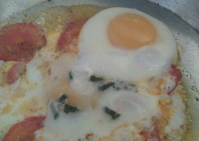 A picture of Sunny side up Eggs with tomato.