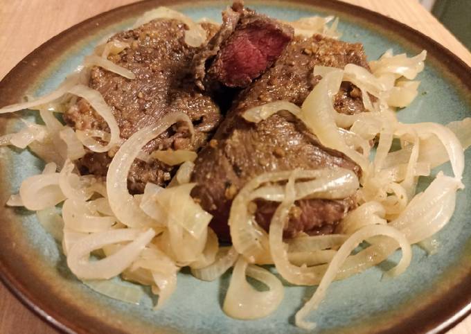 A picture of Steak with onions.