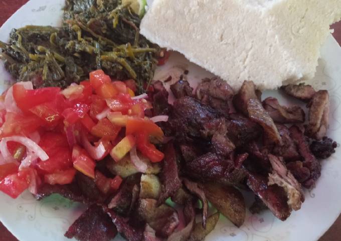 A picture of Nyama choma with traditional vegetables and Kachumbari.