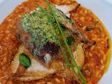 A picture of Tomato and chorizo risotto with pan fried chicken supreme and pesto compound.