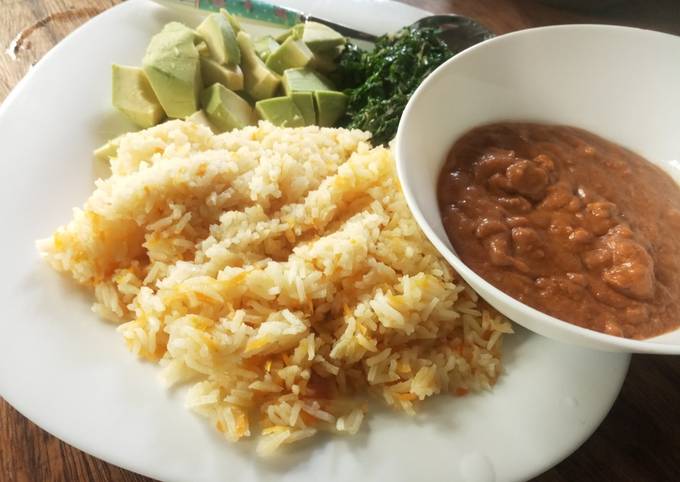 A picture of Carrot cumin rice served with peanut sauce and veggies.