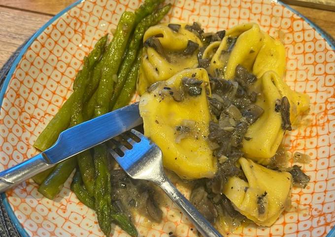 A picture of Truffle tortellini with creamy mushroom and sage sauce, and asparagus side.