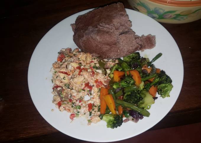 A picture of Brown ugali, fried eggs and mixed vegetables.