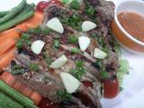 A picture of Moo Kam Waan / Thai style Grilled Pork serve with Spicy Sauce and fresh vegetables.