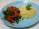 A picture of Mashed potatoes with Broccoli,green peas and carrots.