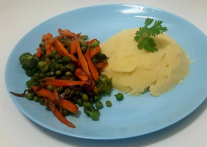 A picture of Mashed potatoes with Broccoli,green peas and carrots.