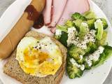 A picture of Egg on toast with sausage, ham and broccoli salad.