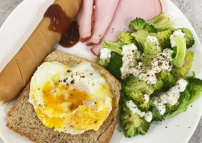 A picture of Egg on toast with sausage, ham and broccoli salad.