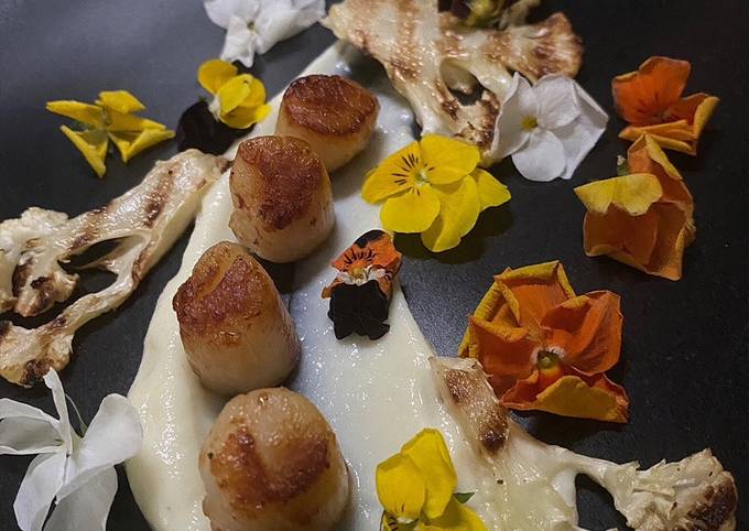 A picture of Seared scallops with cauliflower puree, chargrilled cauliflower and edible flowers.