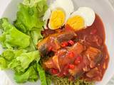 A picture of Spicy canned mackerel in tomato sauce on green noodles.