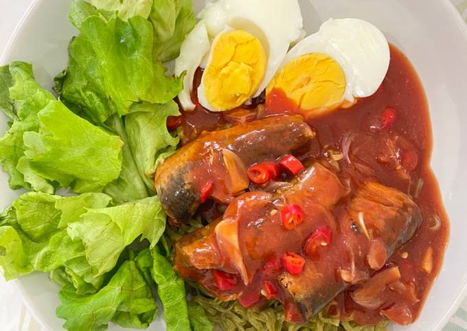 A picture of Spicy canned mackerel in tomato sauce on green noodles.