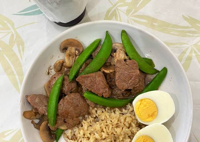 A picture of Stir-fried beef with sugar snap pea and mushroom on rice.