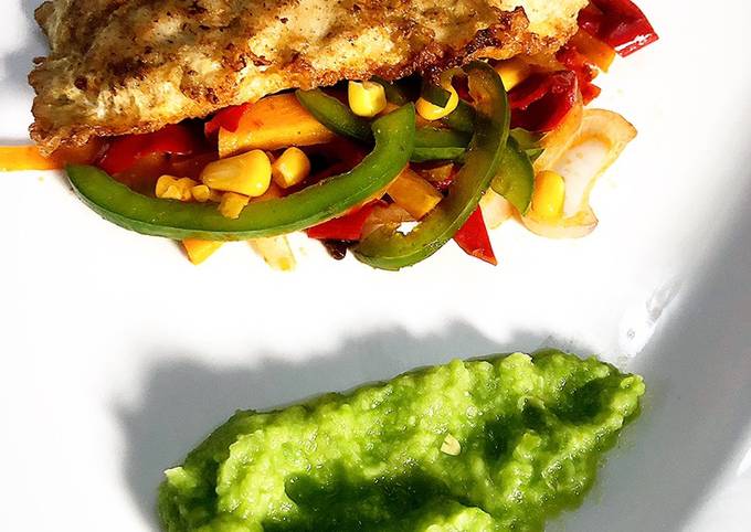 A picture of Deep fried fish fillet on a bed of sautéed vegetables & pea purée.