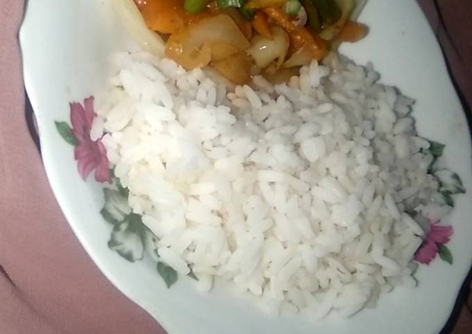 A picture of White rice with vegetable soup.