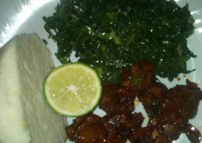 A picture of Fried beef and steamed sukuma wiki.