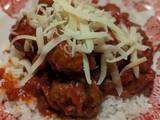 A picture of Beef meatballs in tomato sauce and rice.