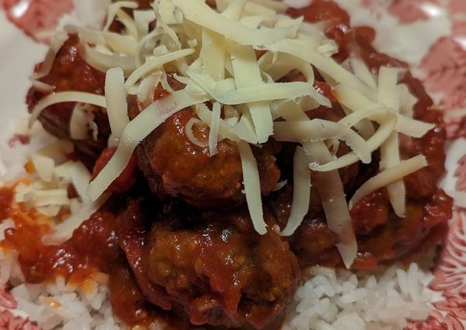 A picture of Beef meatballs in tomato sauce and rice.