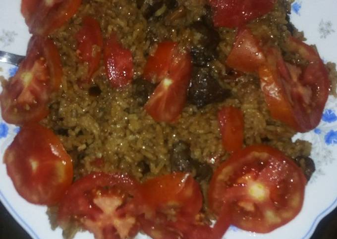 A picture of Beef pilau garnished with tomatoes.