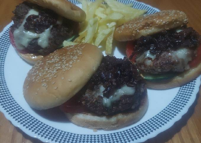 A picture of Beef-lamb burger with caramelized onions,cheese, tomato&cucumber.