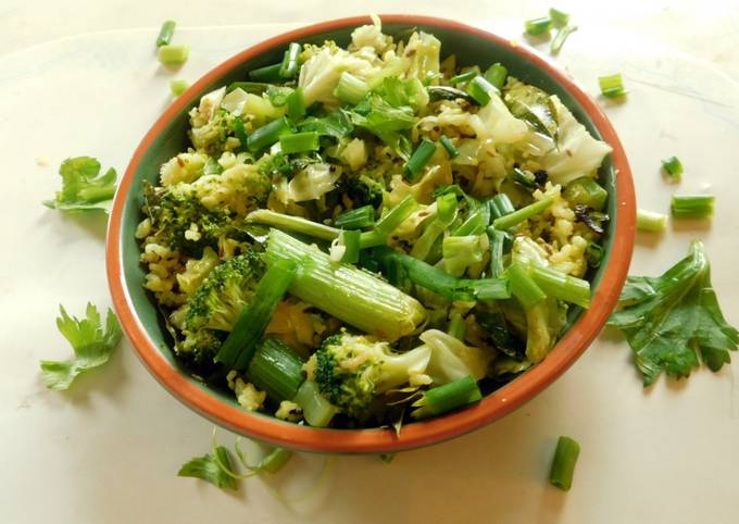 A picture of Fried rice topped with green veggies.