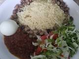 A picture of Cooked couscous and beans with sauce and vegetables.