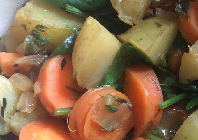 A picture of Vegetable curry with carrots, carrot tops, potatoes and spinach.