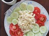 A picture of Scrambled eggs with tomato and cucumber salad.