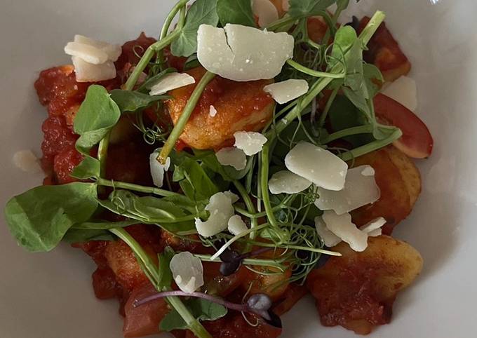 A picture of Gnocchi with mushrooms, tomato sauce and parmesan shavings.