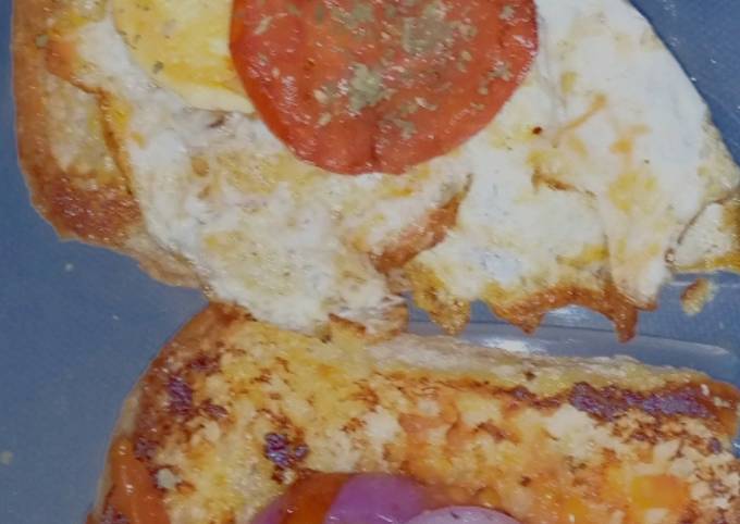 A picture of Bun-egg toast topped with sauted onions and tomatoes.